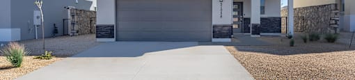 A modern house with a large driveway in front.