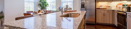 A kitchen with a granite countertop and stainless steel appliances.