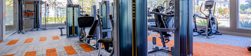A gym with orange carpet and treadmills.