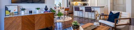 A modern living room with a wooden cabinet, a blue rug, and a ceiling fan.