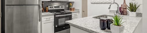 A modern kitchen with a stainless steel refrigerator, microwave, oven, and sink.