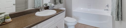 A white bathroom with a brown counter top and a white toilet.