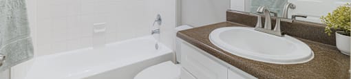 A white toilet sits next to a white bathtub in a bathroom.