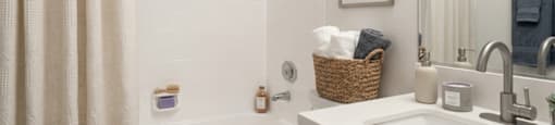 A bathroom with a white tub, sink, and shower curtain.