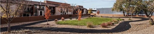 a circle of grass and trees in front of a building