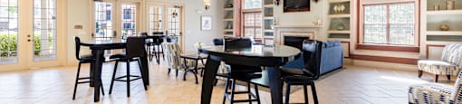 Rapallo Apartments community clubhouse seating area with 2 bar tables and 2 chairs at each table.