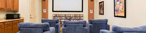 Rapallo Apartments community theater room with a screen mounted on the wall, individual sofa chairs and a movie library