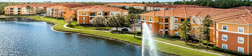 a fountain in the middle of a lake with an apartment complex in the background