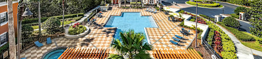 an aerial view of the resort style pool with lounge chairs and palm trees