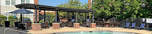 A large outdoor pool with a patio and umbrellas.