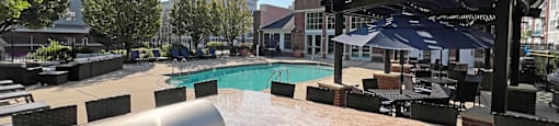 A BBQ grill is on a patio next to a pool.