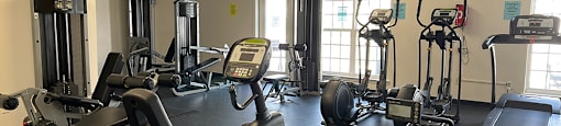 A gym with treadmills, elliptical machines, and a television.