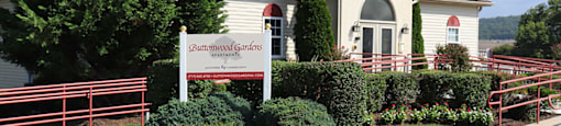 A sign for Butterfly Gardens stands in front of a building.