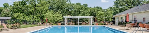 A large outdoor swimming pool surrounded by trees and a pavilion.