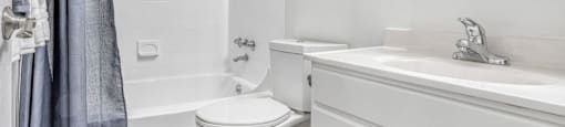 A white bathroom with a toilet, sink, and shower.