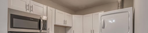 A kitchen with white cabinets and a microwave above the stove.
