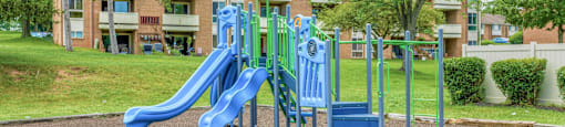 A playground with a blue slide and a green tree.