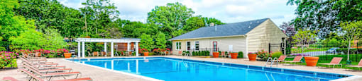 A pool with sun loungers and a house in the background.