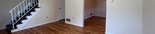 A room with wooden flooring and a staircase.