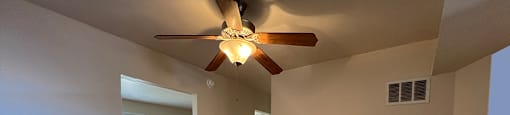 A room with a ceiling fan and wooden flooring.