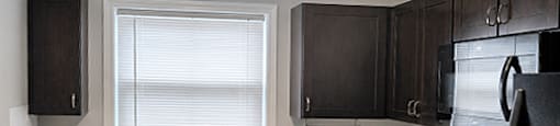 A kitchen with black appliances and brown cabinets.
