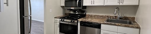 A kitchen with a granite countertop and stainless steel appliances.