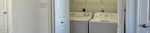 A white laundry room with a washer and dryer.