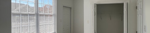 A room with a ceiling fan and a window with blinds.