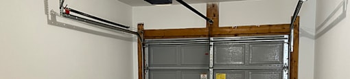A large metal garage door is closed and has a yellow sign on it.