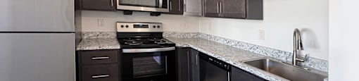 A kitchen with dark wood cabinets and a stainless steel refrigerator.