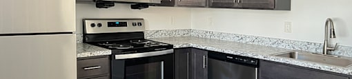 A kitchen with a white fridge, black stove, and black cabinets.