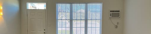 A room with a ceiling fan and a window with blinds.