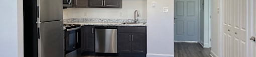 A kitchen with a black fridge and stainless steel appliances.