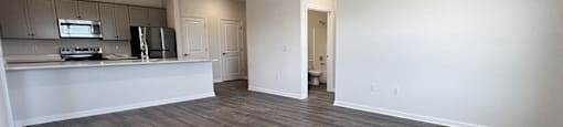 an empty living room and kitchen with wood flooring