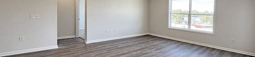 an empty living room with wood floors and a window