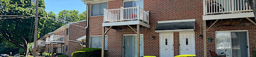 A brick apartment building with a white balcony on the second floor.