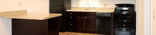 Ktchen with black modern appliances and wooden cabinets.