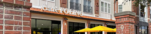 A yellow umbrella is on a table outside of a restaurant.