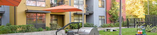  BBQ Area with Grilling Station, Table and Benches, Grassy Lawn with Cornhole Board, and Building Exterior in the Background  at FREMONT MEWS, California, 95814