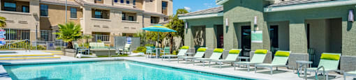 A swimming pool with sun loungers and a building in the background.