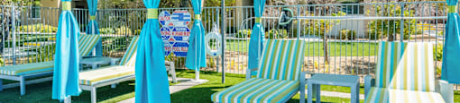 A sunny day at the park with blue and yellow striped chairs and umbrellas.