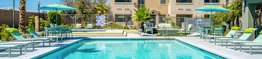 A large swimming pool in front of a building with a palm tree.