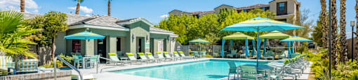 A sunny day at the pool with palm trees and a building in the background.