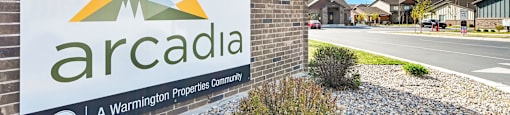 A sign for Arcadia, a Warminston Properties Community, is displayed in front of a building.