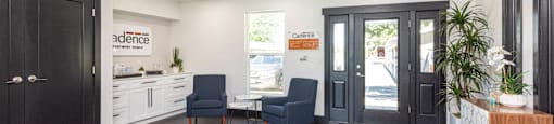 a living room with two chairs and a table and a door at Cadence Apartments, Roy Utah