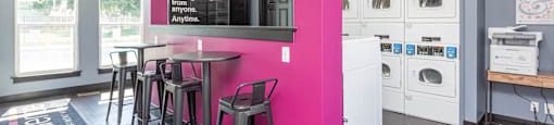 a kitchen with a pink pillar and a bar with stools at Cadence Apartments, Roy, UT