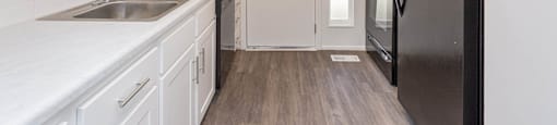 a kitchen with white cabinets and a black refrigerator at Cadence Apartments, Roy