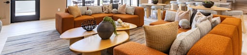 A modern living room with a large orange sofa and a wooden coffee table.