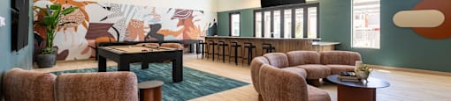 A room with a mural on the wall and a long couch.