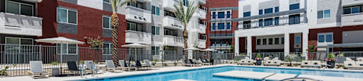A pool with a diving board in front of apartment buildings.